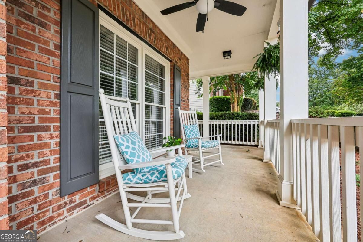 Covered brick-house porch with two white rocking chairs, turquoise cushions, and a ceiling fan.