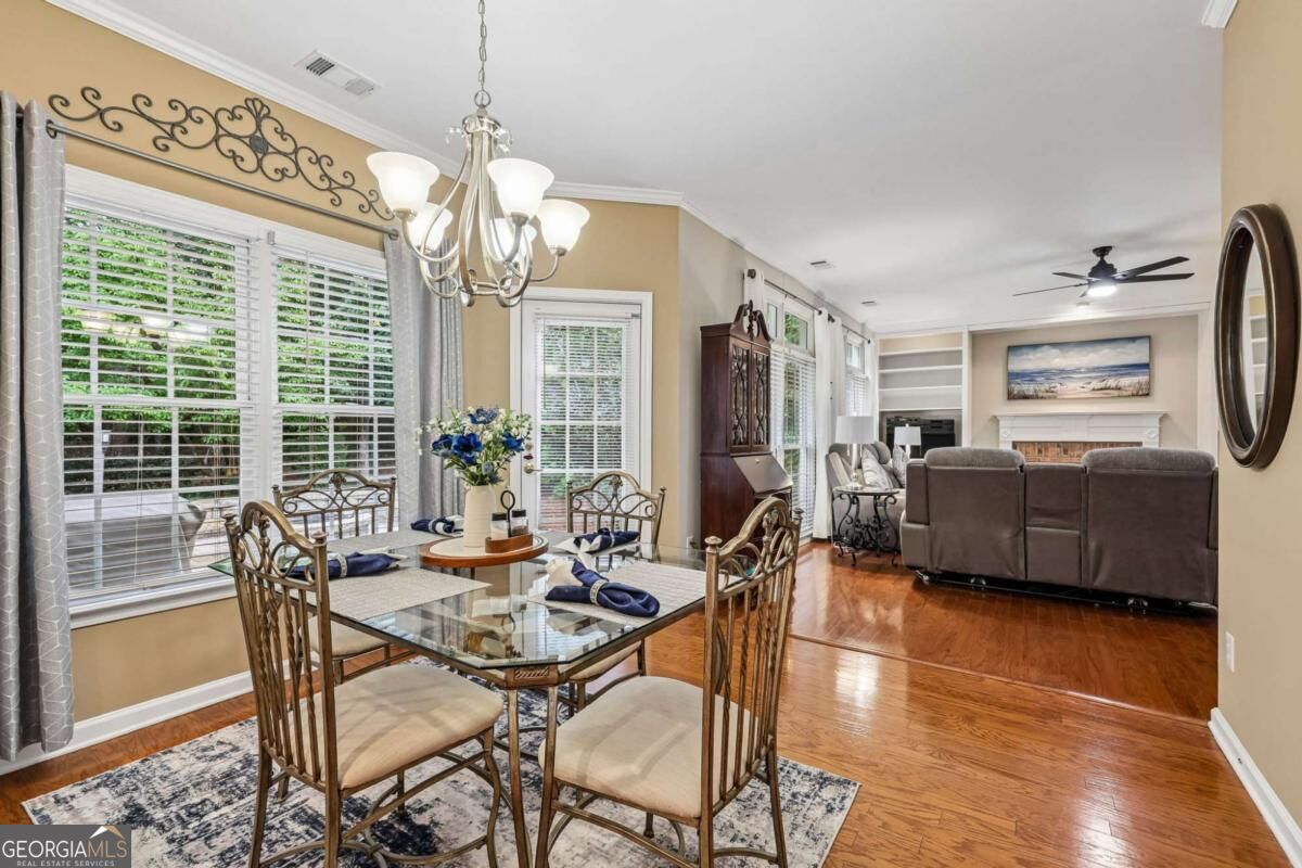 Dining room opening into a living room, with a glass-top table, hardwood floors, and a fireplace.