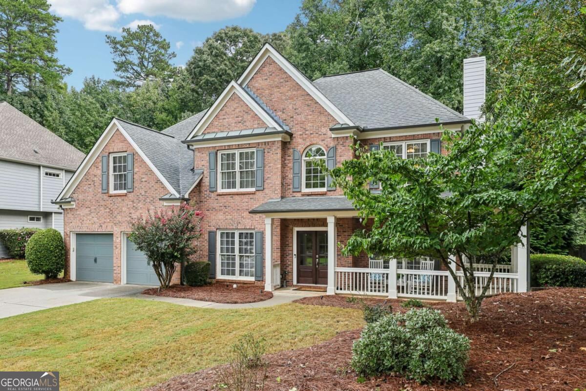 Two-story brick home with a double garage, covered porch, and landscaped front yard.