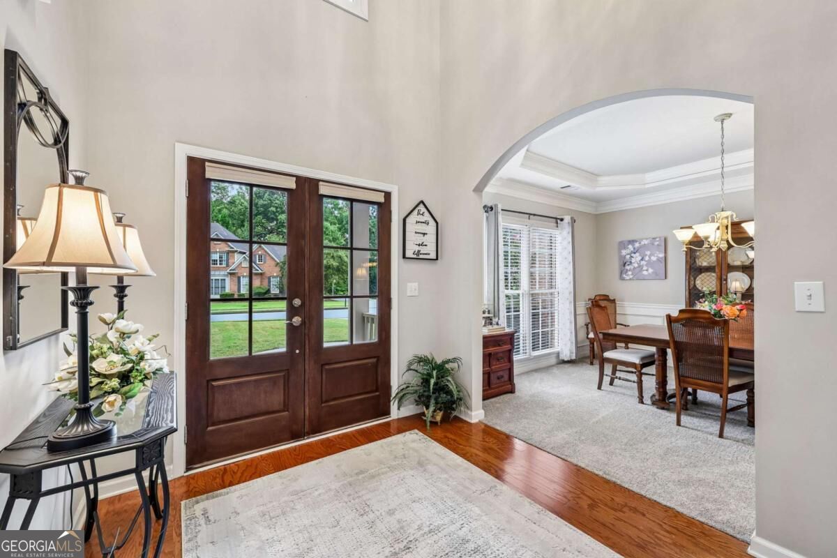 Entry foyer with dark wood double doors and an arched opening to the dining room.
