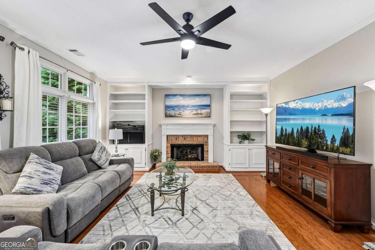 Living room with gray sectional, fireplace, built-in shelves, and large windows.