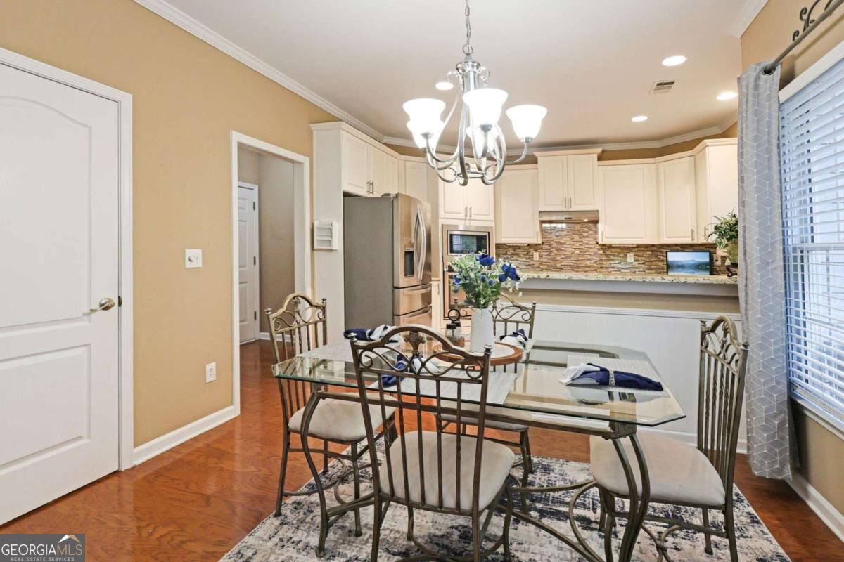 Kitchen and dining area with white cabinetry, stainless appliances, and a glass-top dining table.