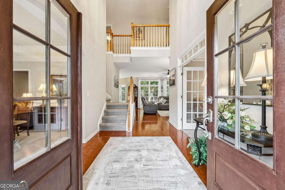 Two-story foyer with open French doors, a carpeted staircase, and hardwood floors.