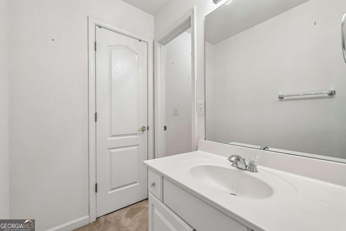 Bathroom with a white vanity, oval sink, large mirror, and paneled door.