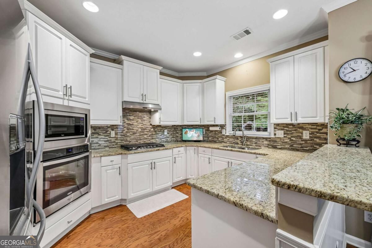 Kitchen with white cabinets, stainless steel appliances, and a granite-topped peninsula.