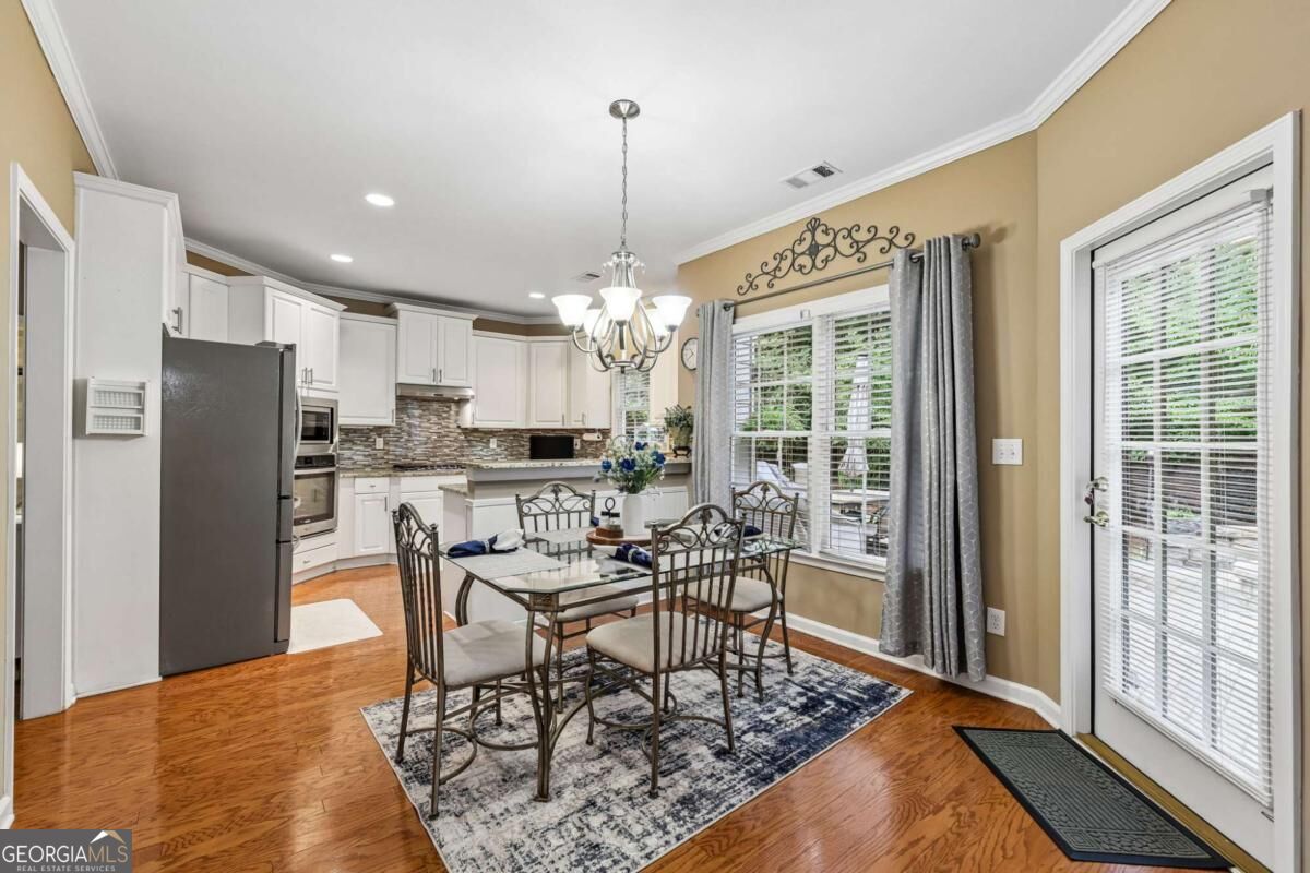 Kitchen and dining area with white cabinets, stainless appliances, and a glass-top table.