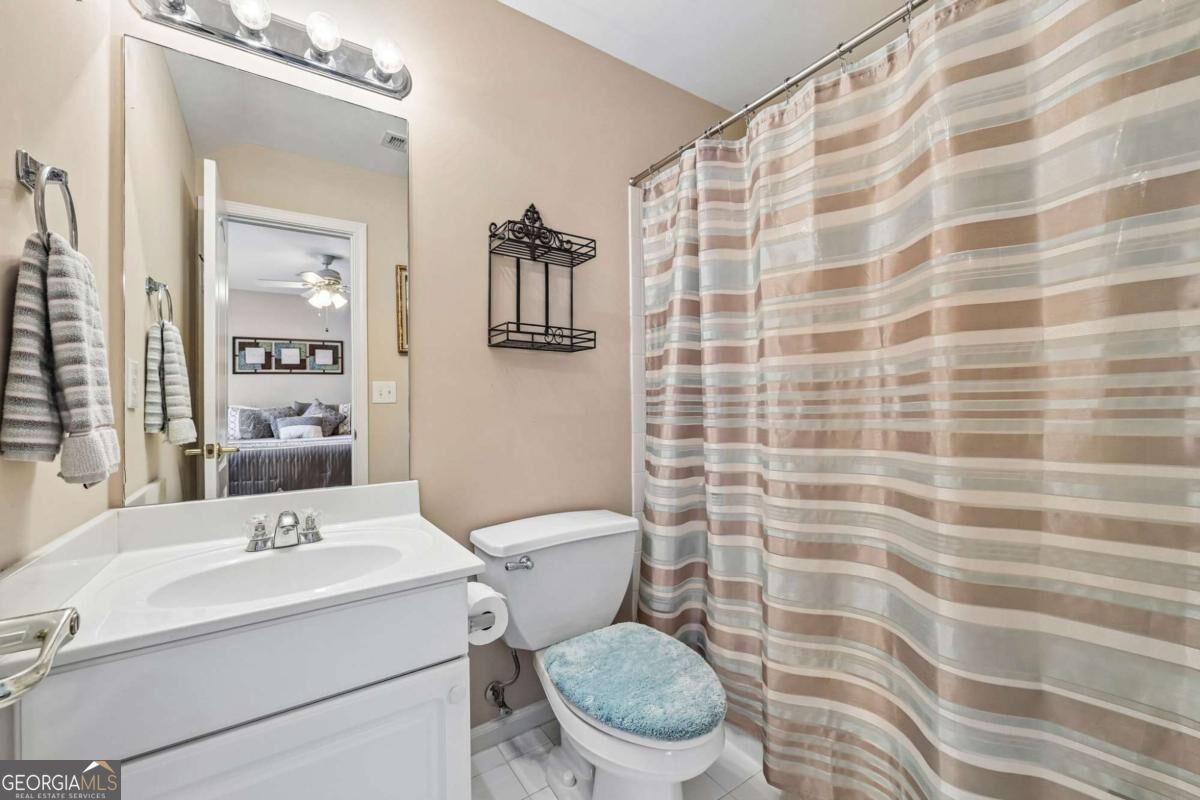 Bathroom with a white vanity, toilet, and striped shower curtain.