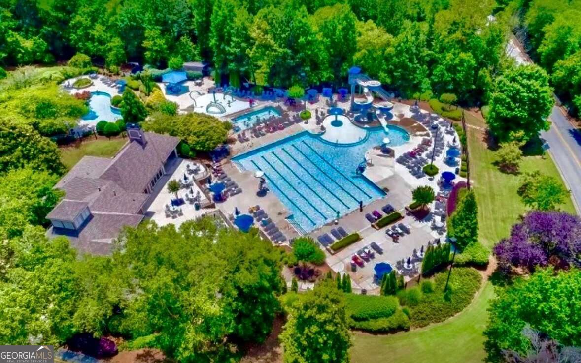 Aerial view of a community pool with lap lanes, water slides, and a clubhouse.