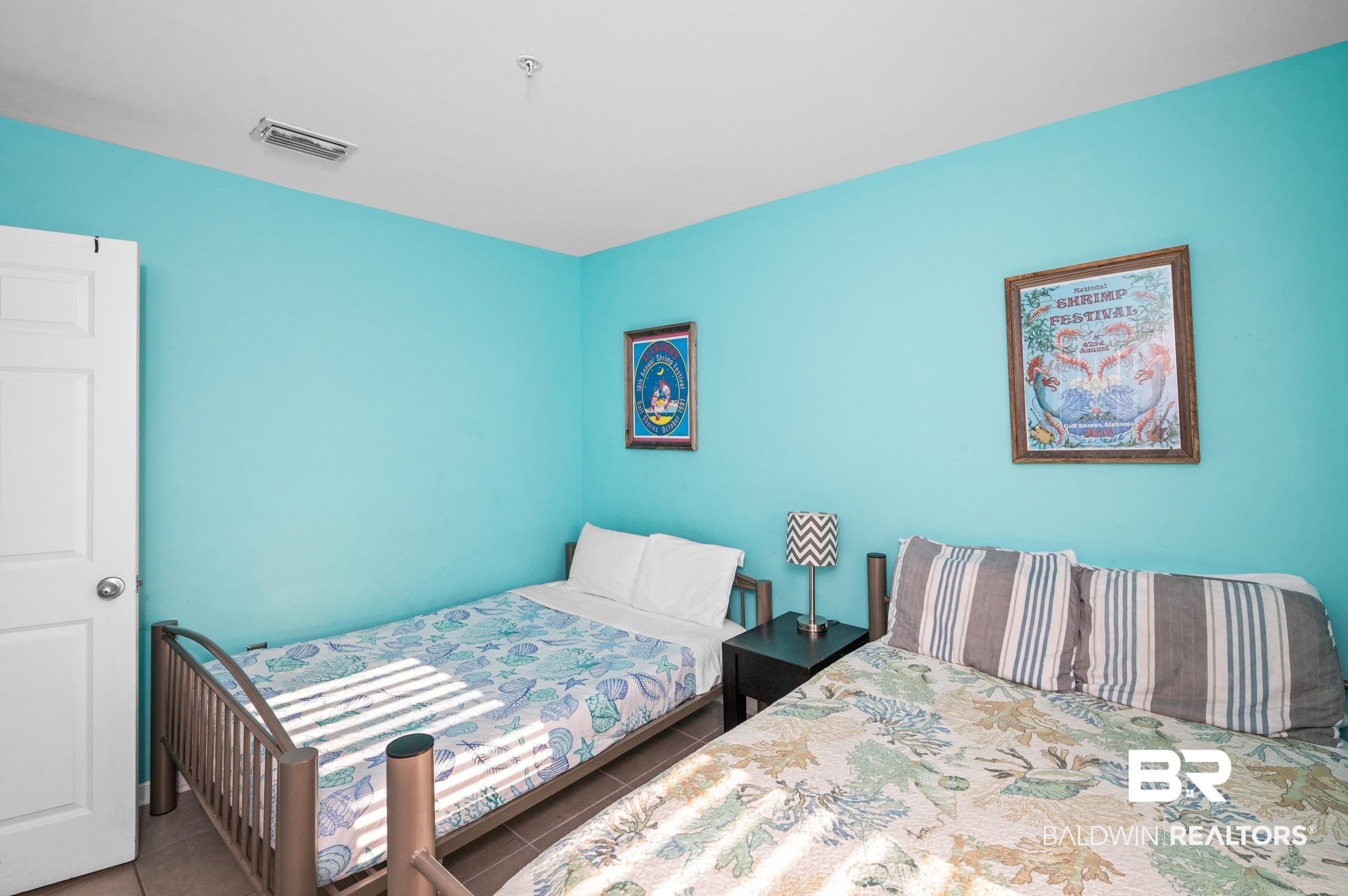 Bedroom with two beds, turquoise walls, and coastal-patterned bedding.