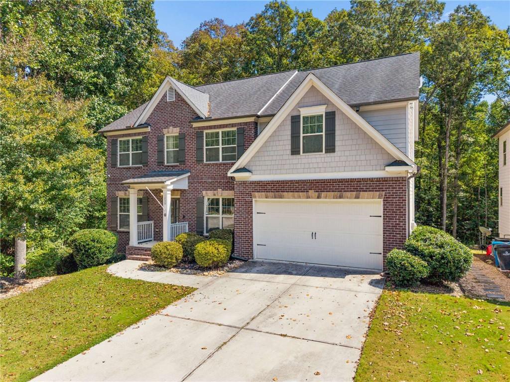 Two-story brick-and-siding home with a double garage, covered porch, and wide driveway.