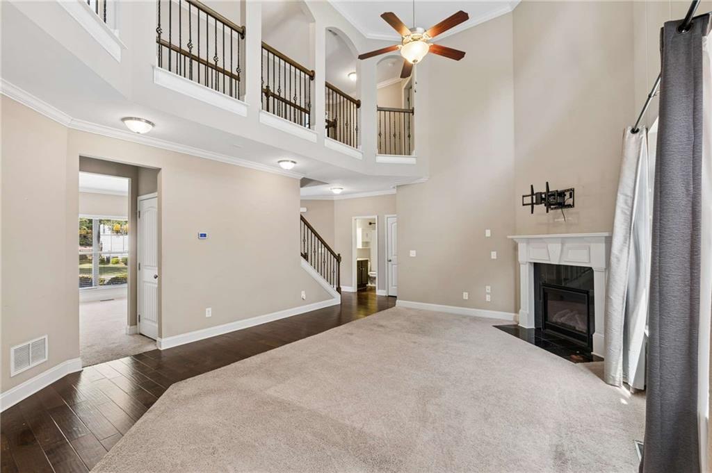 Two-story living room with a fireplace, ceiling fan, and open upstairs landing.