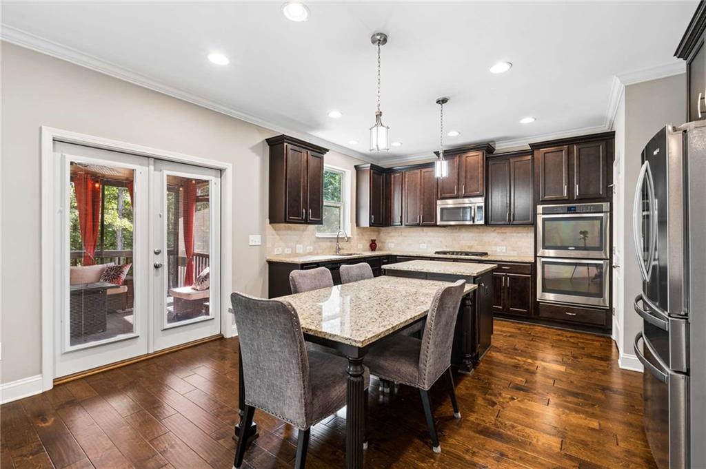 Kitchen with dark wood cabinets, granite island, stainless steel appliances, and doors to a screened porch.