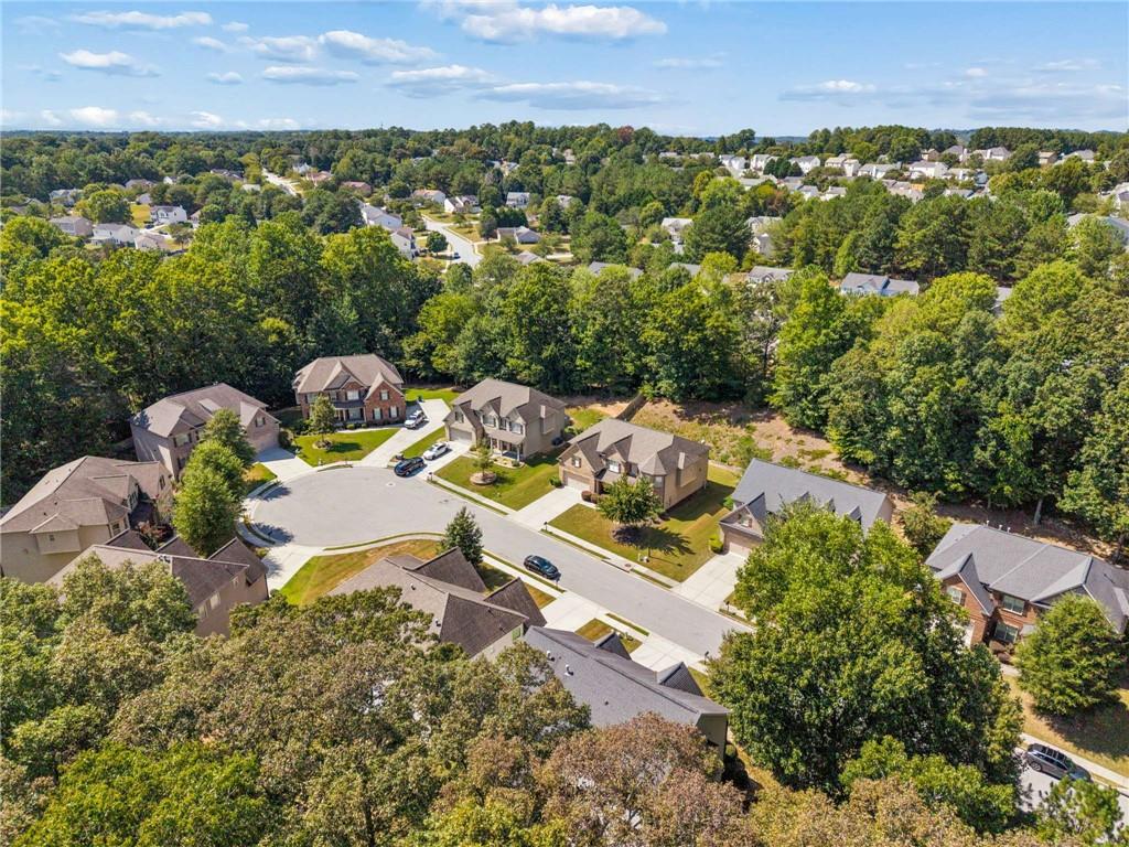 Aerial view of homes around a cul-de-sac, with mature trees and a wooded neighborhood beyond.