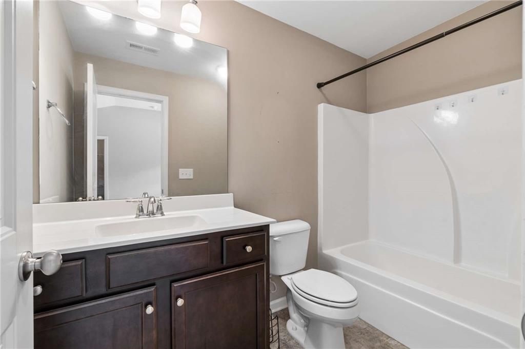 Bathroom with a dark wood vanity, white sink, toilet, and tub-shower surround.