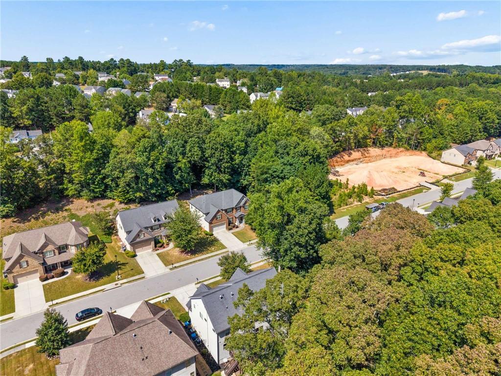 Cleared residential lot bordered by trees, with nearby homes and streets.