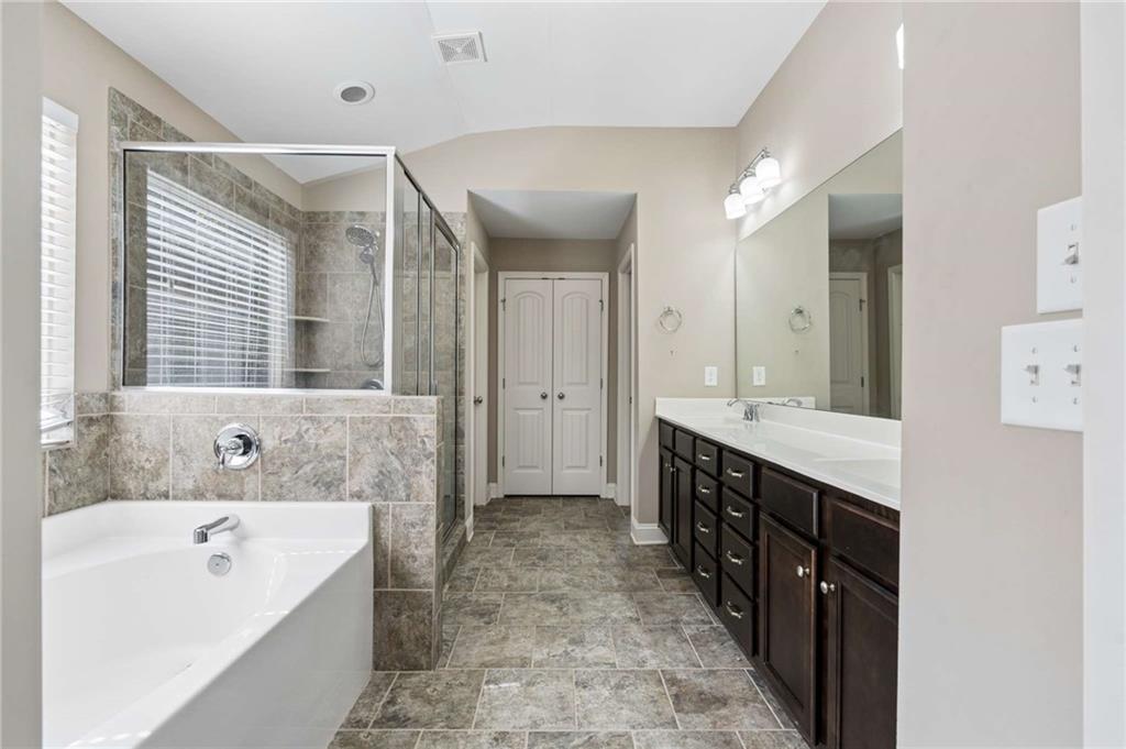 Bathroom with a soaking tub, tiled glass shower, and long dark double vanity.
