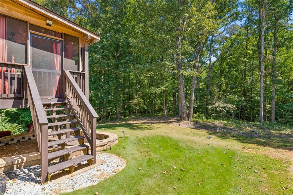Home’s wooden deck stairs open onto a grassy, wooded backyard.