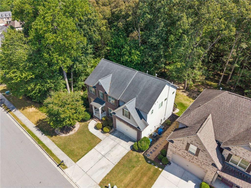 Aerial view of a two-story house with an attached garage, driveway, and mature trees.