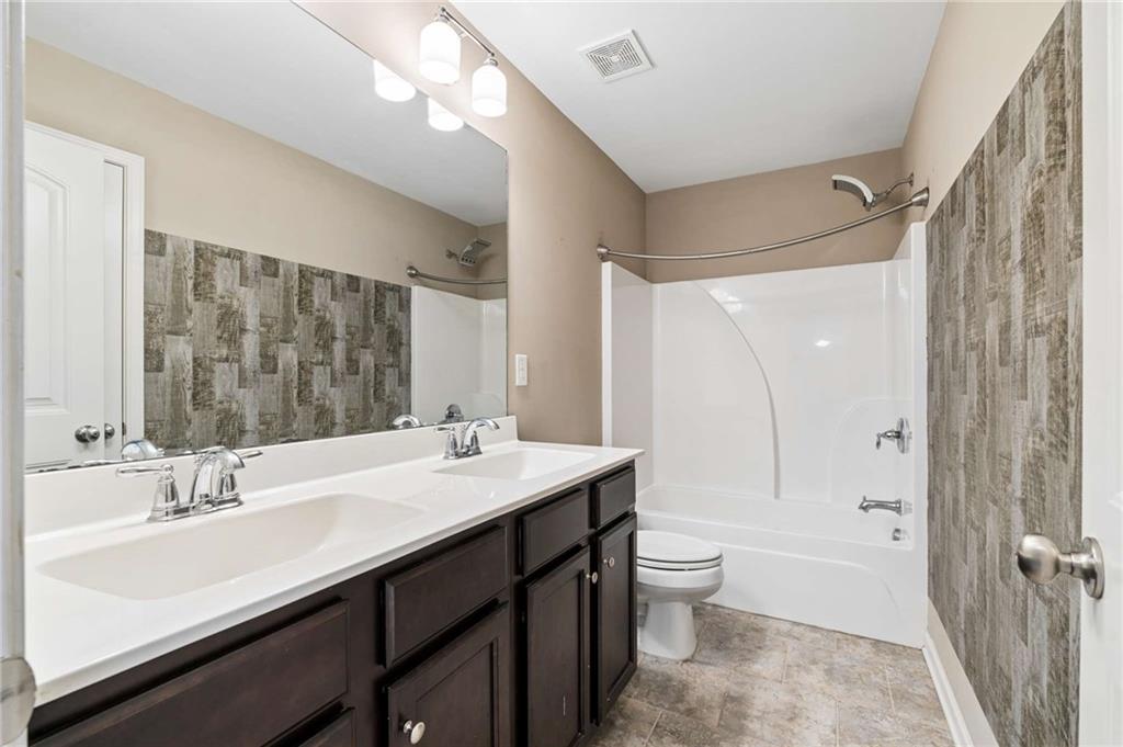 Bathroom with a dark double vanity and a white tub-shower with gray patterned tile.