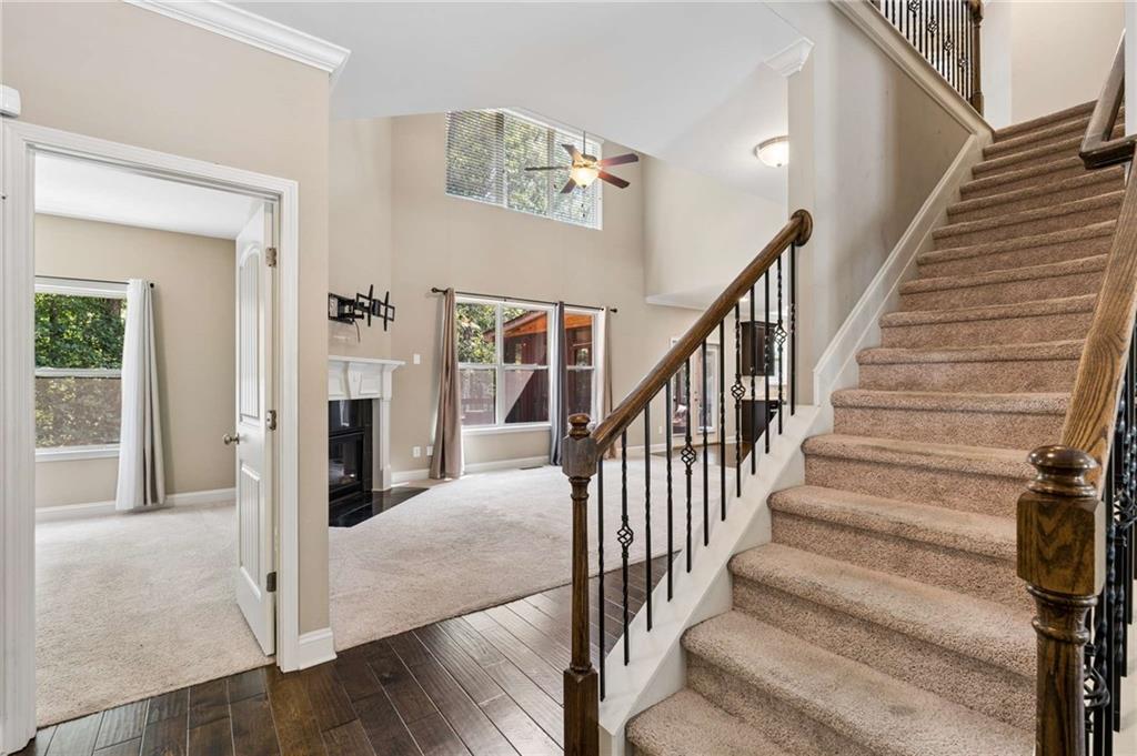 Entry hall with a carpeted staircase leading past an open living room and fireplace.