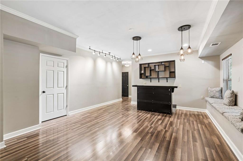 Finished interior with wood-look floors, a cushioned window bench, and a dark counter beneath wall shelving.
