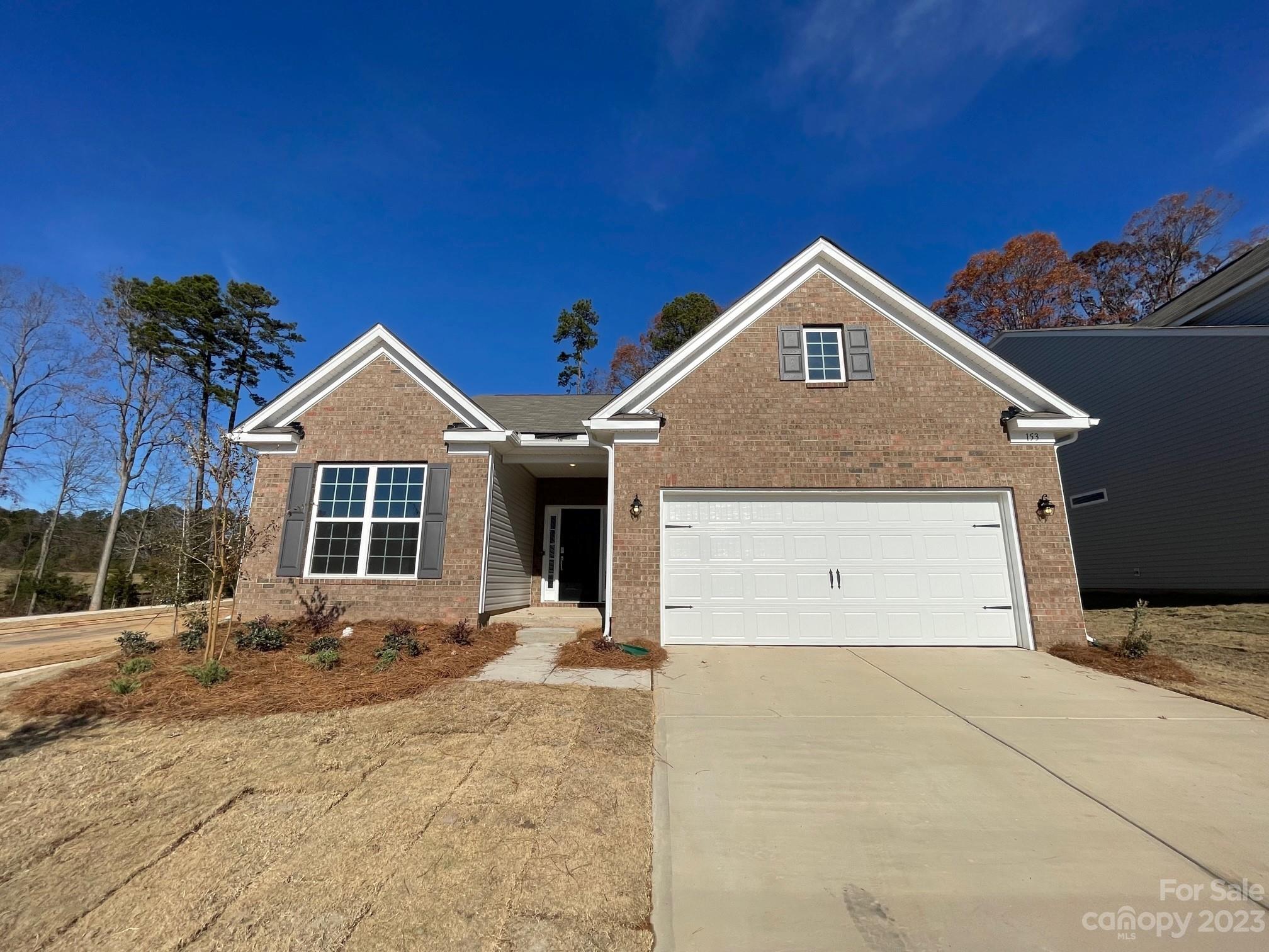 Brick house with a two-car garage, recessed entry, and broad concrete driveway.