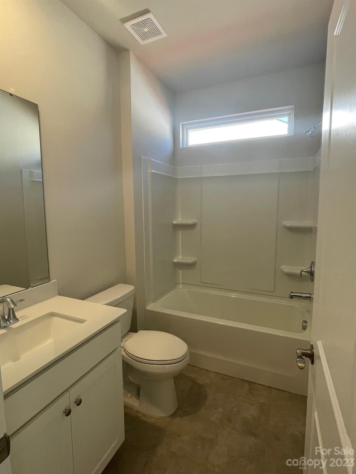 Bathroom with a white vanity, toilet, and bathtub with a built-in shower.
