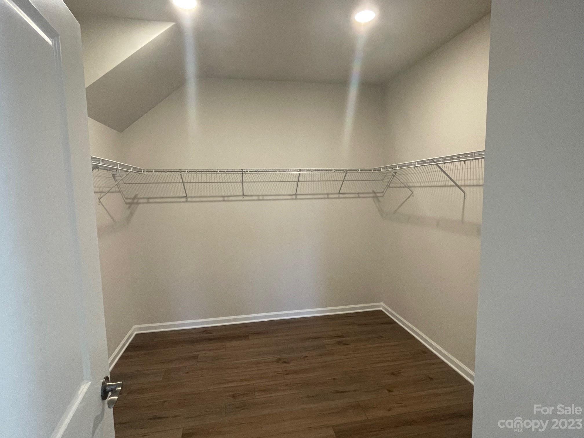 Empty walk-in closet with dark flooring and wire shelving along three walls.