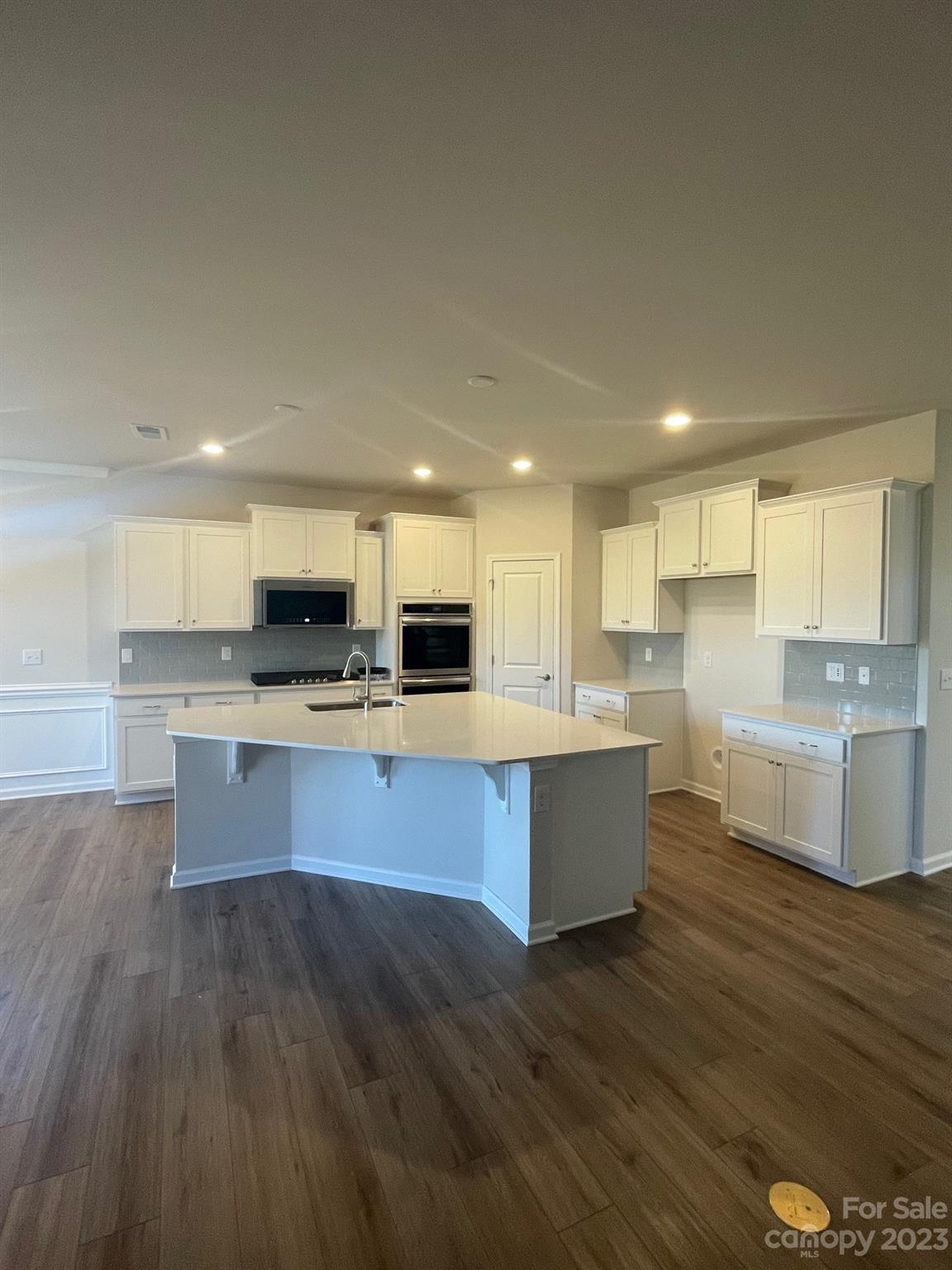 Kitchen with white cabinets, stainless steel appliances, and a large central island.