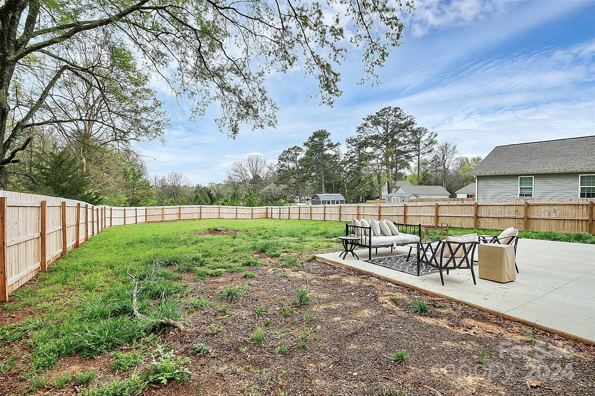Fenced backyard with a grassy lawn and a furnished concrete patio.