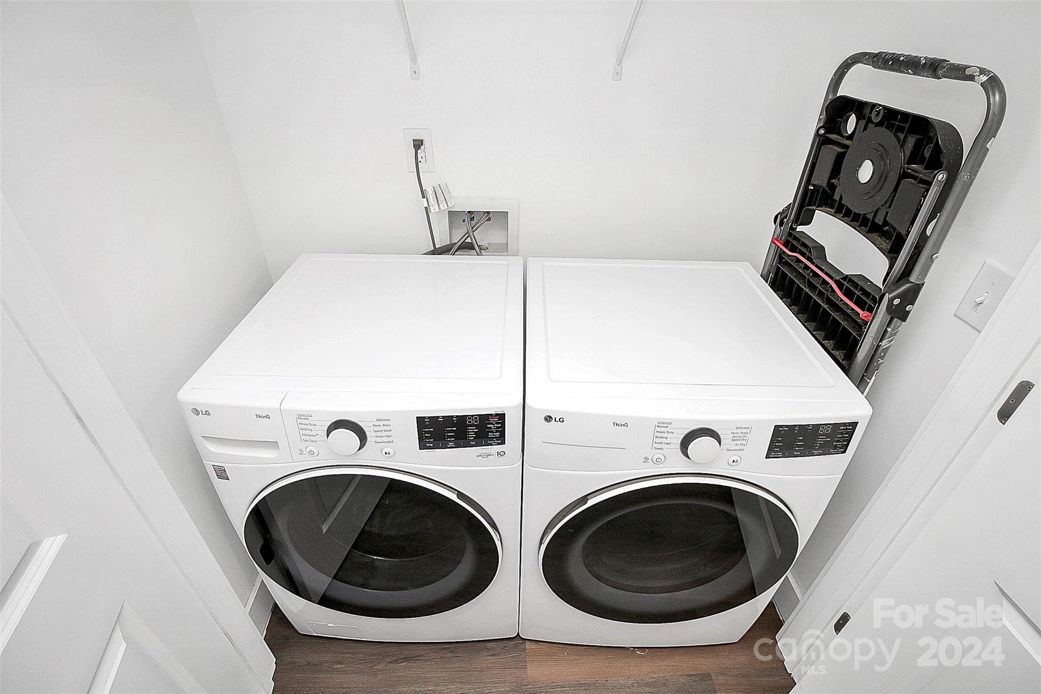 Laundry room with side-by-side white front-loading washer and dryer and a folding step ladder.