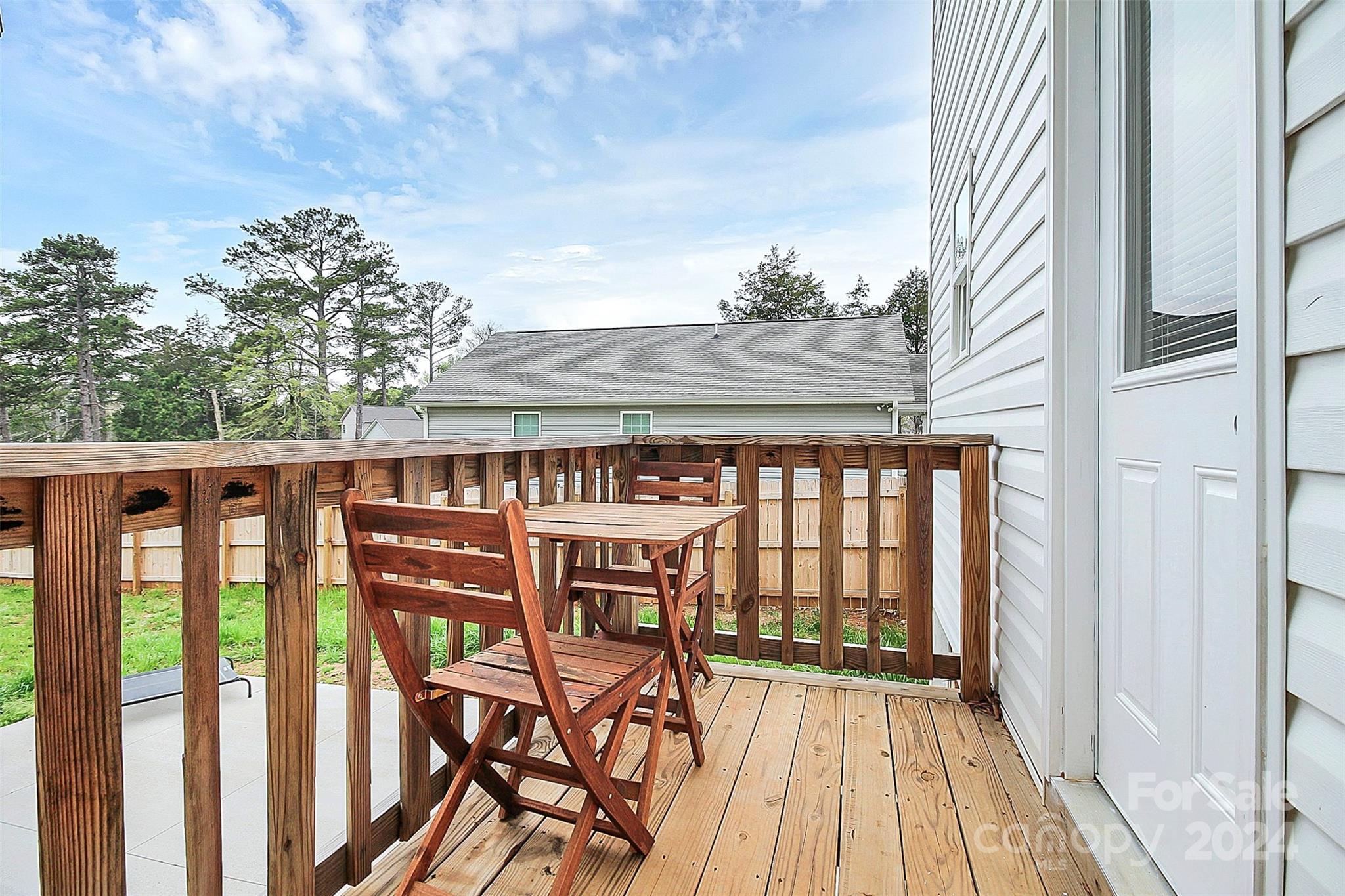 Wooden deck furnished with a table and folding chairs beside the home.