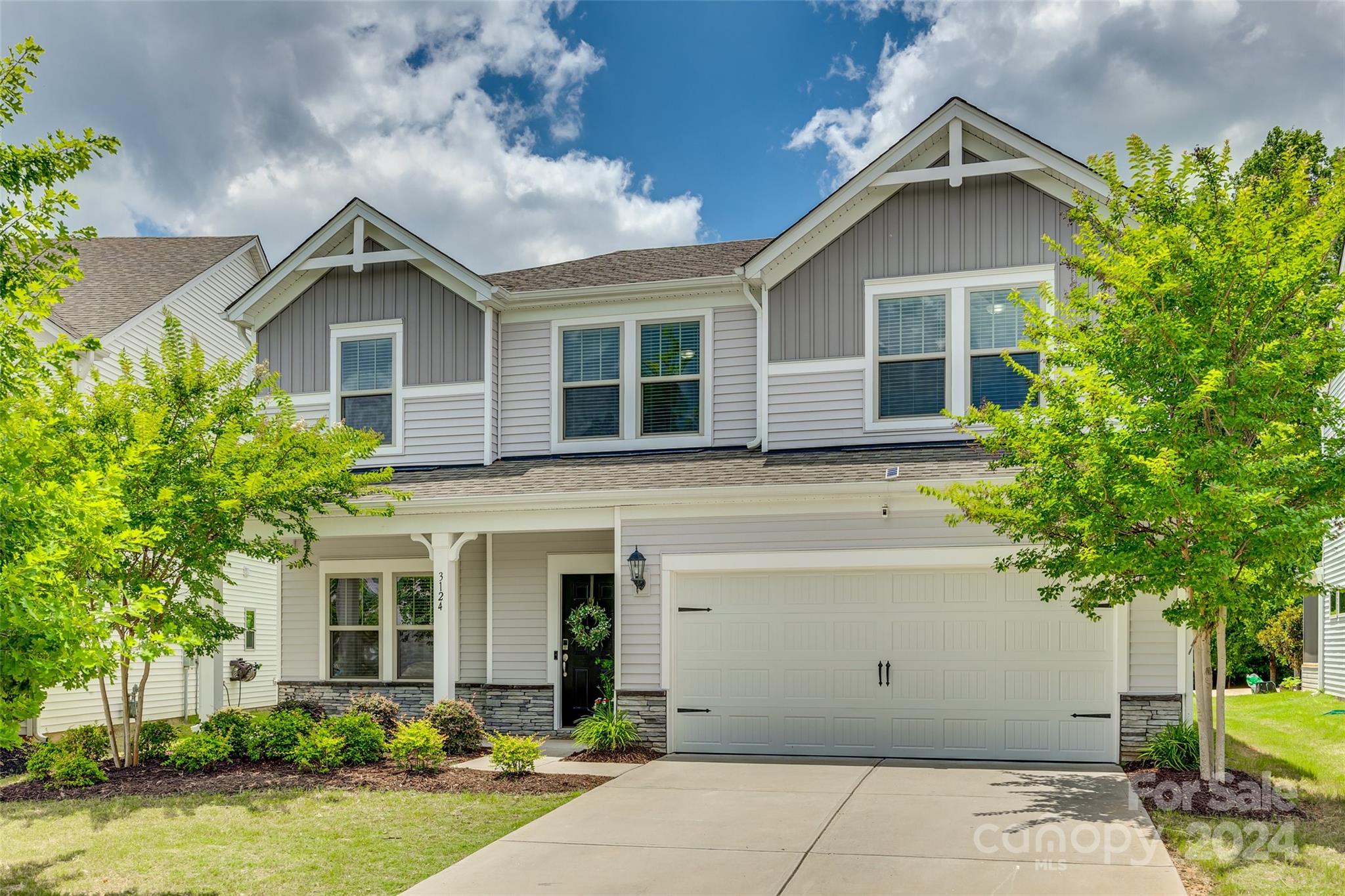 Two-story gray-and-white house with twin gables, stone accents, and a two-car garage.