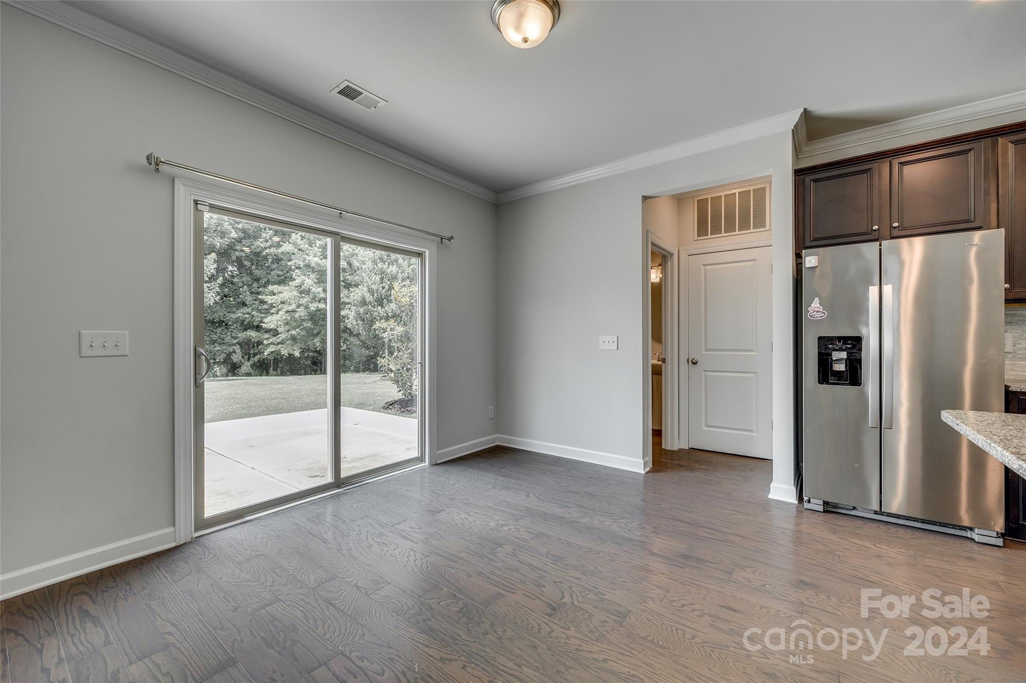 Empty kitchen and dining area with stainless steel refrigerator and sliding glass doors to the patio.