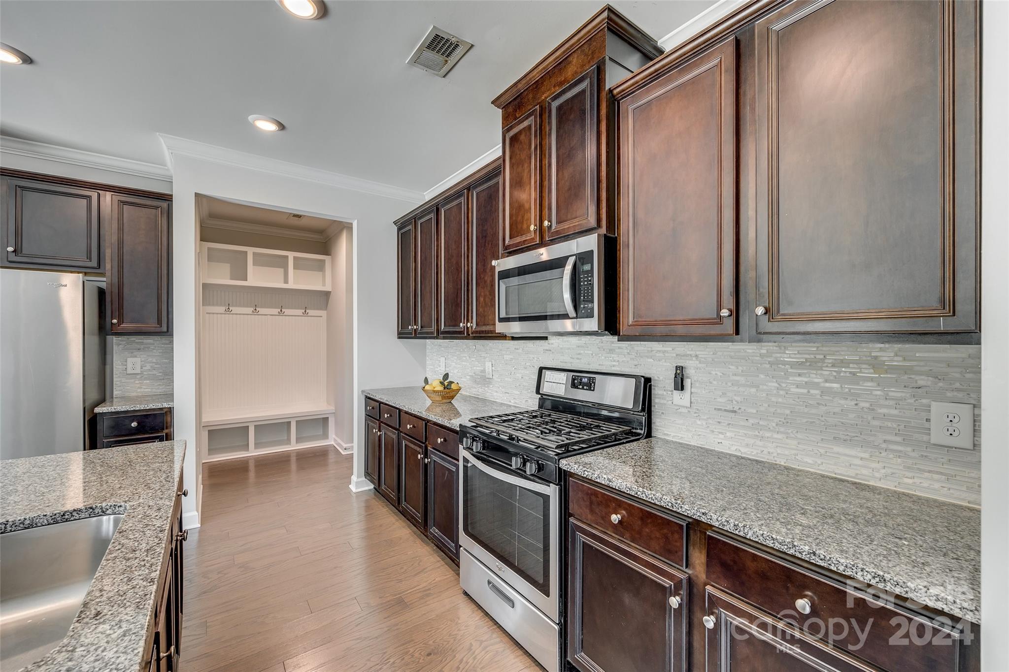 Kitchen with dark wood cabinets, granite counters, stainless appliances, and a gas range.