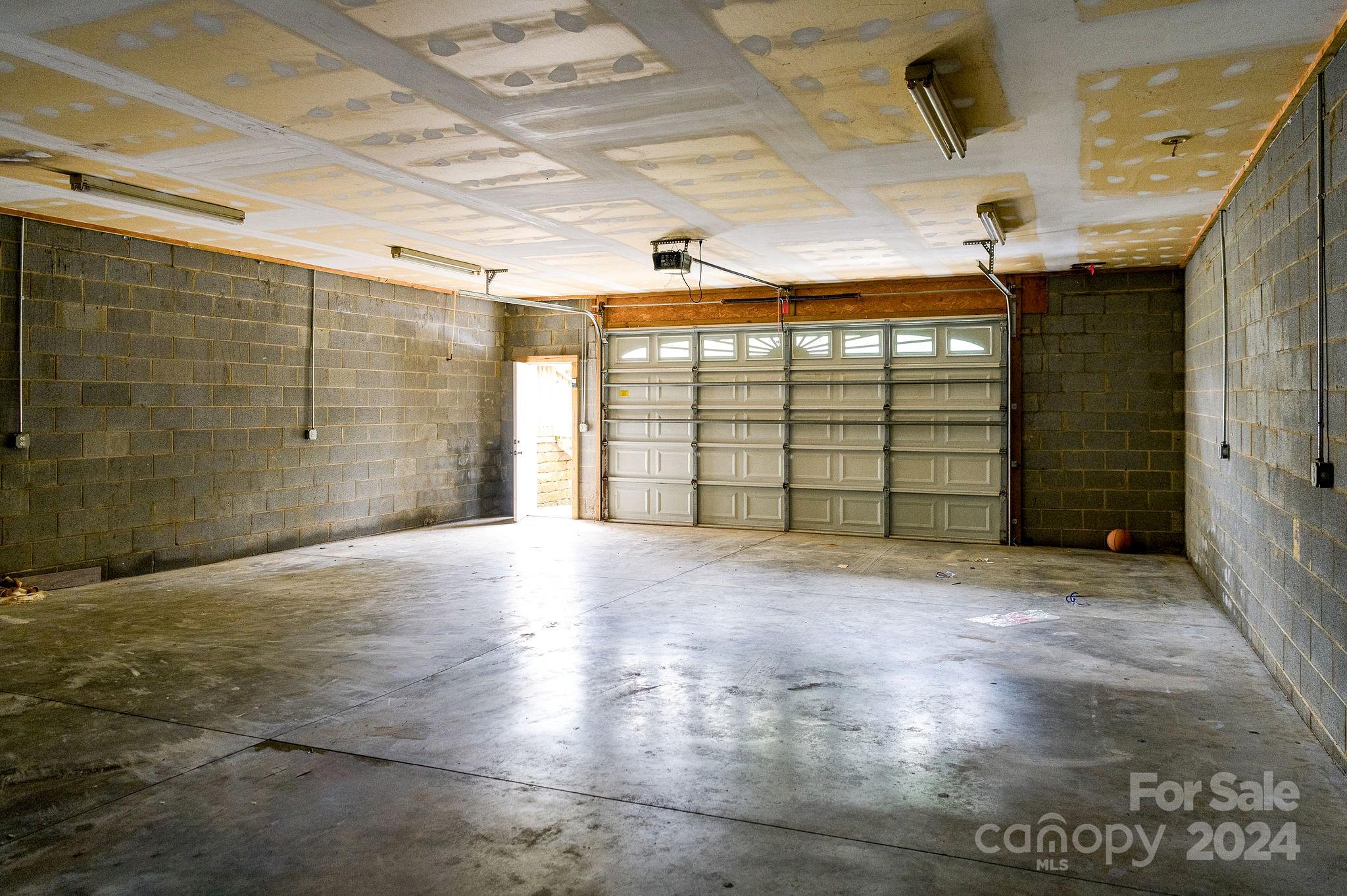 Empty two-car garage with concrete-block walls, unfinished ceiling, and paneled overhead door.