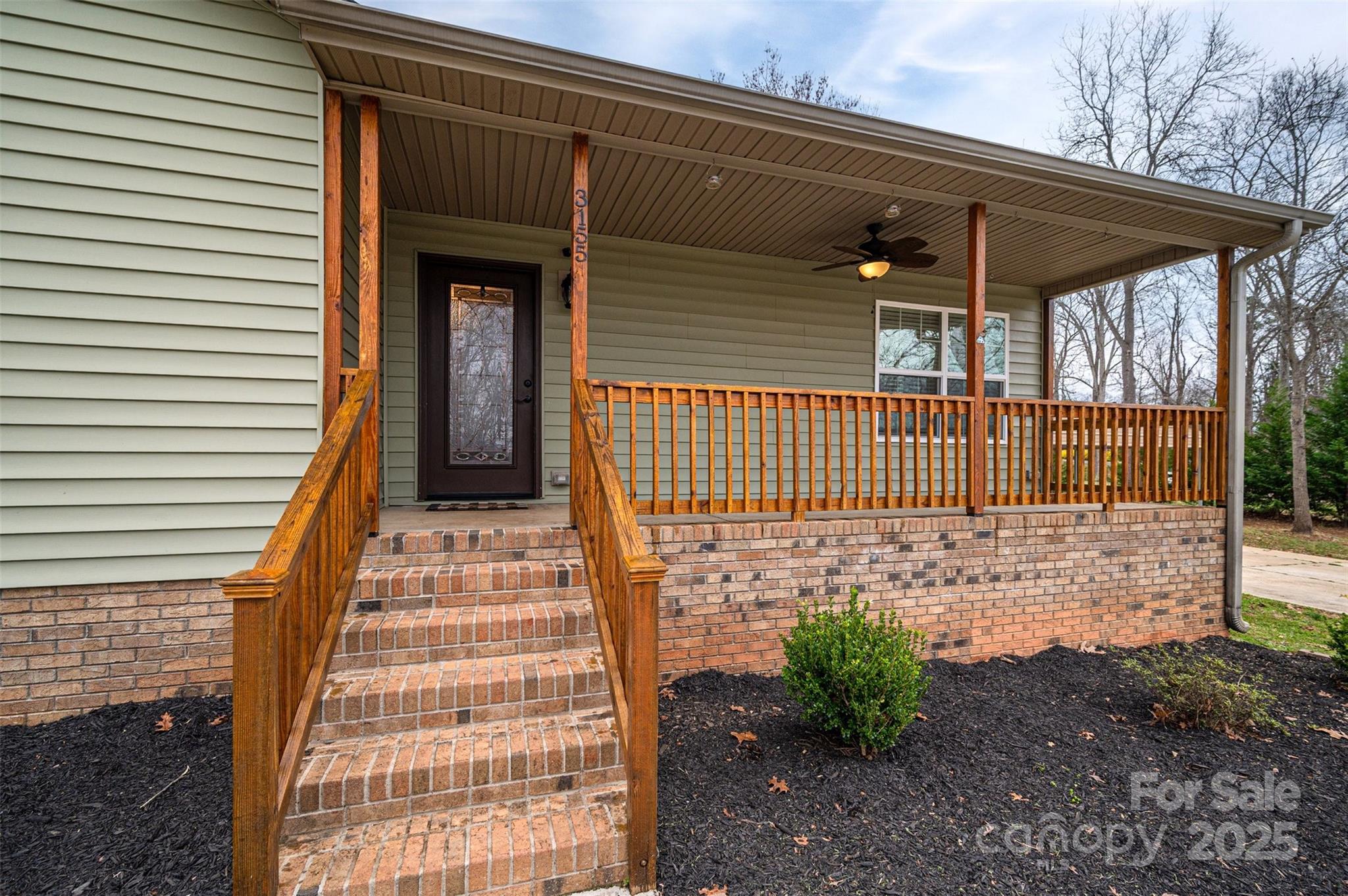 House exterior with a covered porch, brick steps, and wooden railings.