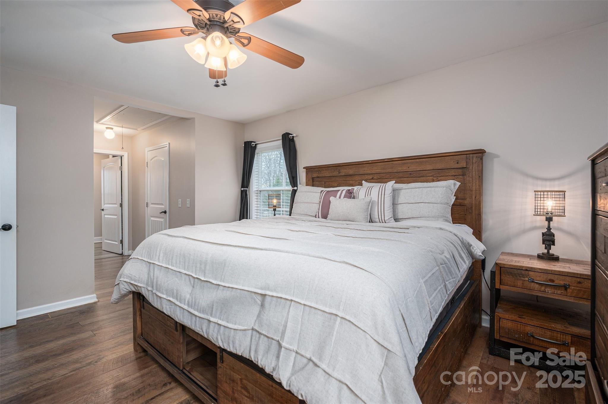 Furnished bedroom with a large wooden bed, white bedding, and a ceiling fan.