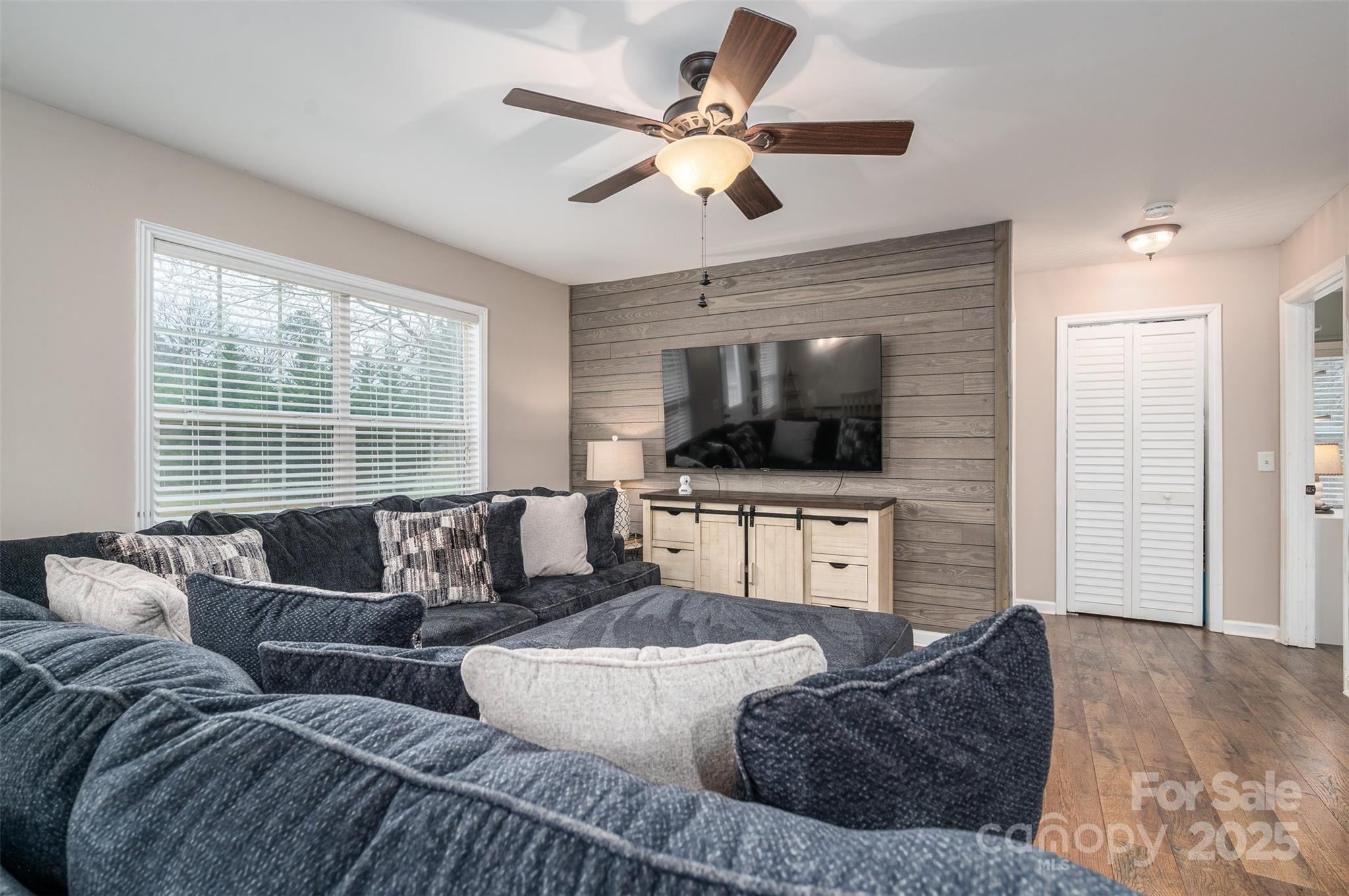 Living room with a dark sectional facing a TV on a gray wood-plank accent wall.