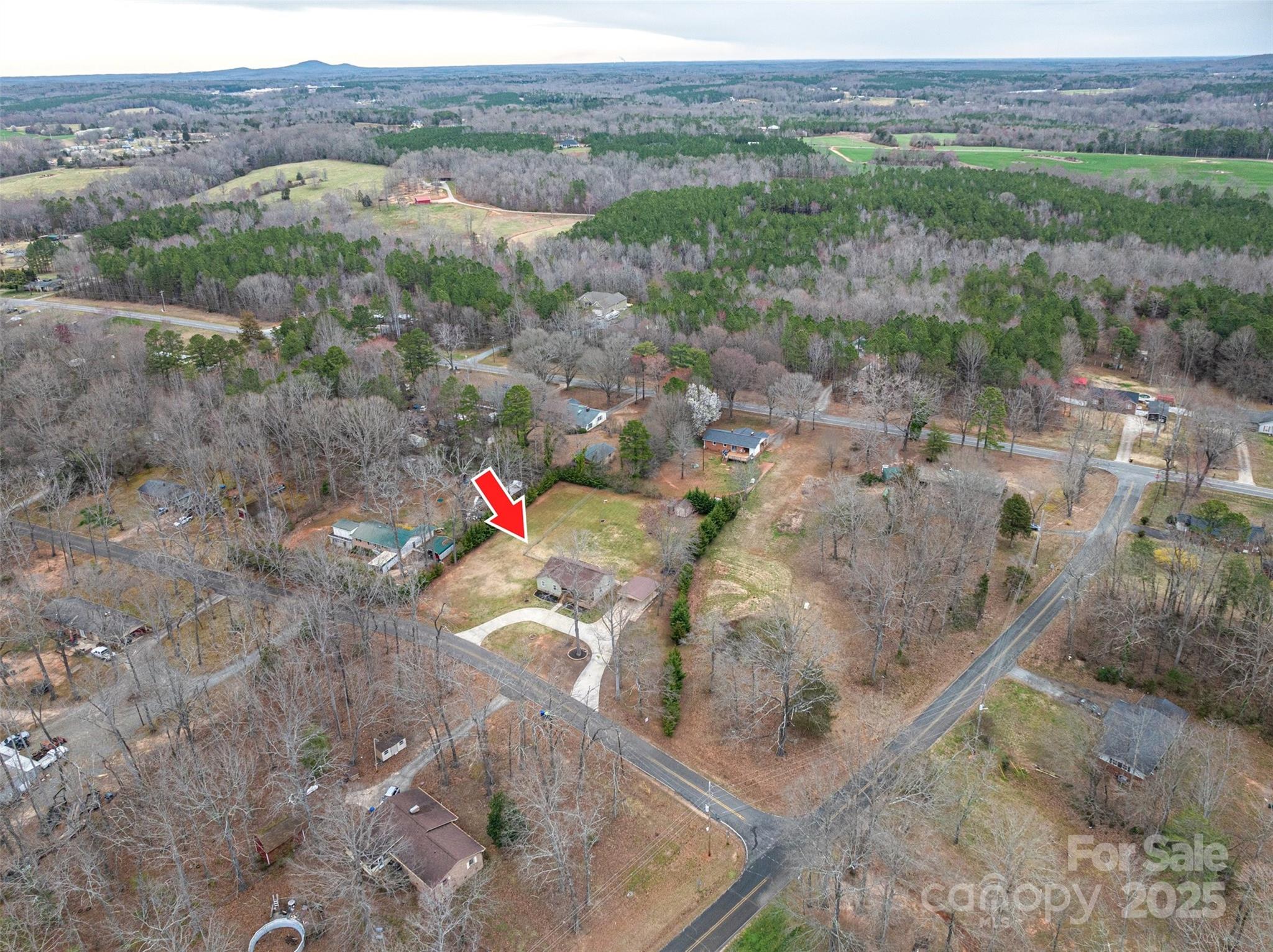 Aerial view of a home and lot marked by a red arrow among wooded residential streets.