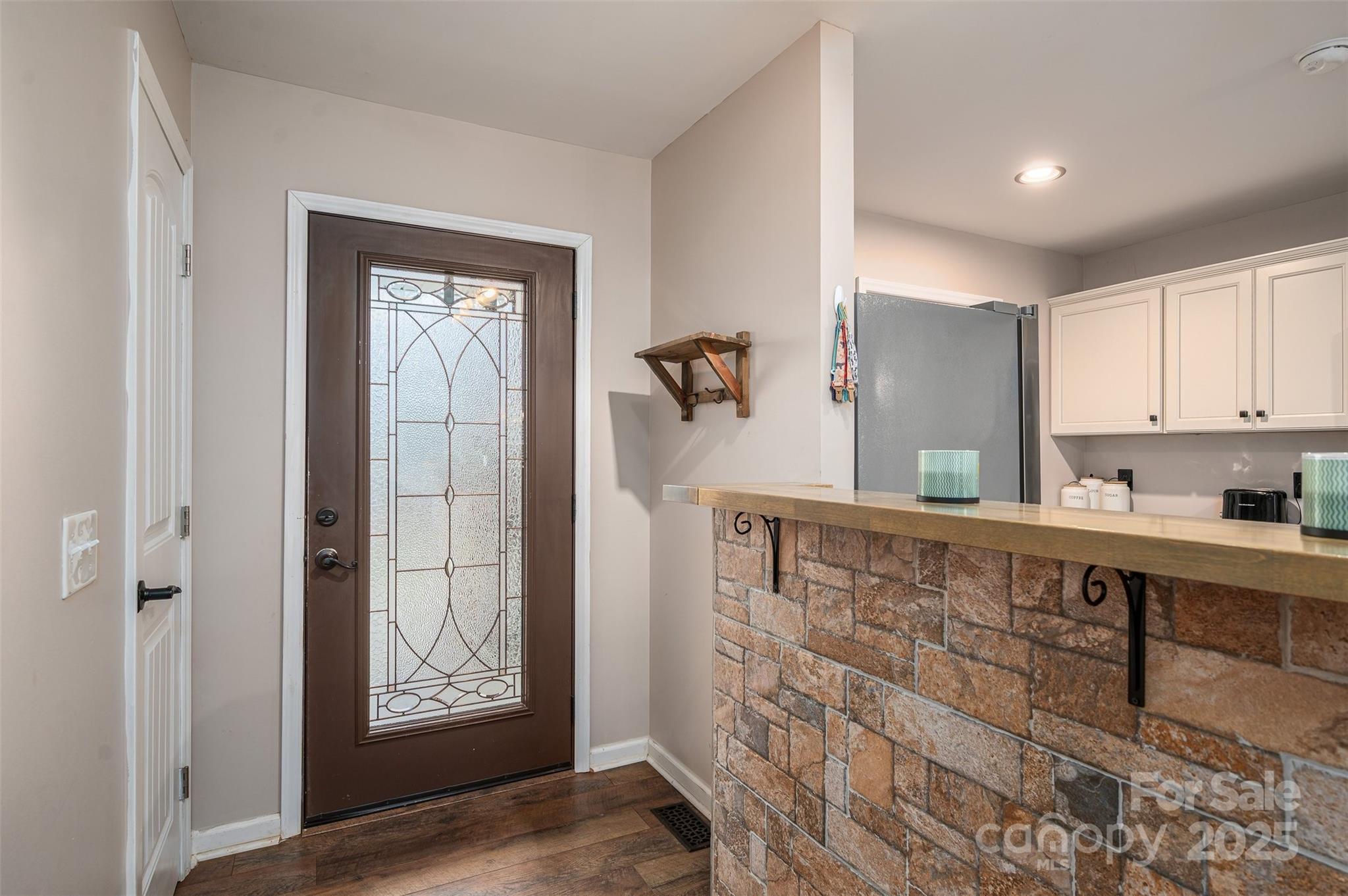 Kitchen and entryway with a decorative glass front door and stone-front counter.