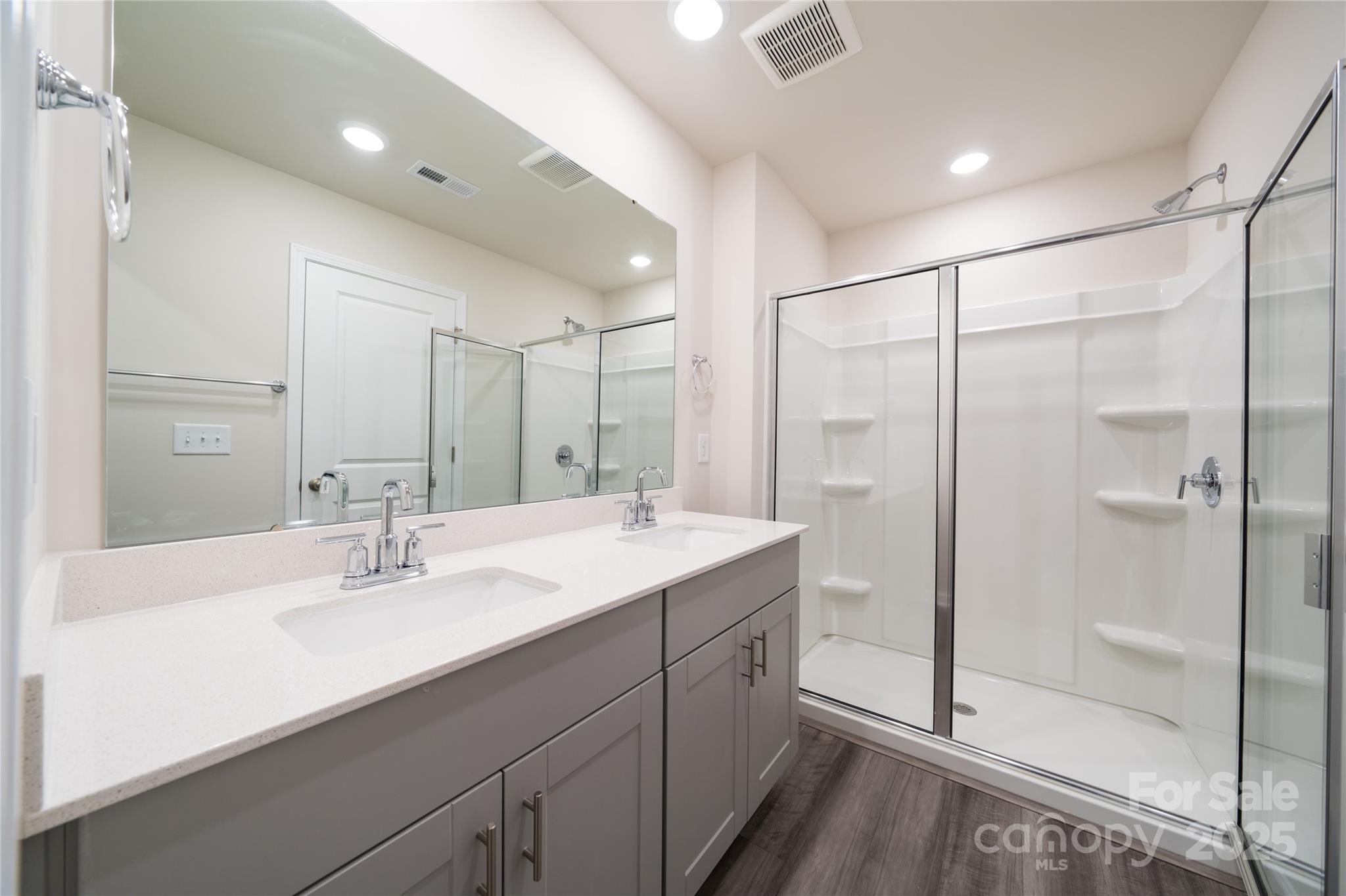 Bathroom with a double vanity and a glass-enclosed shower with built-in shelves.