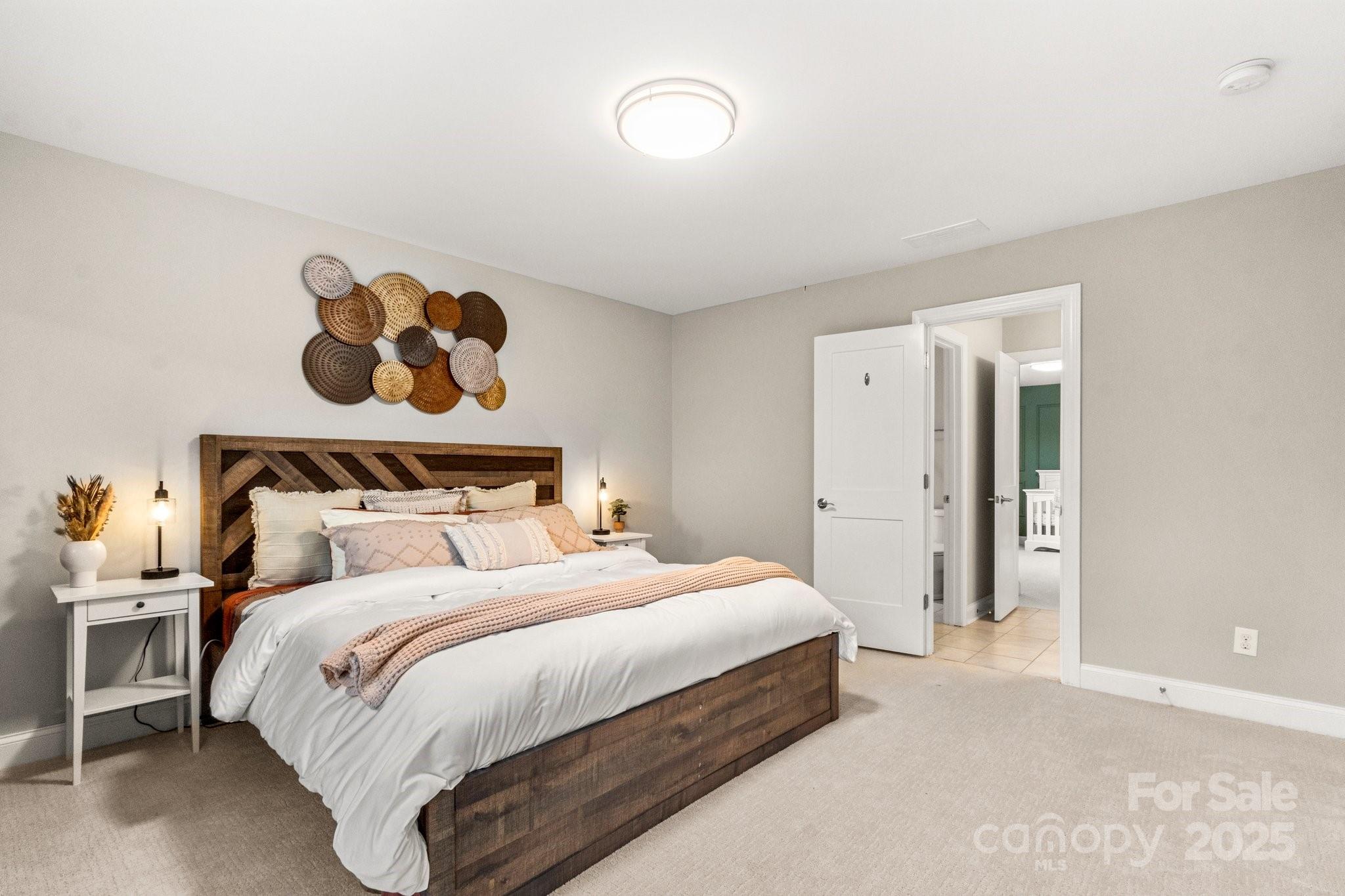 Staged bedroom with a wooden bed, white bedding, and woven circular wall decor.