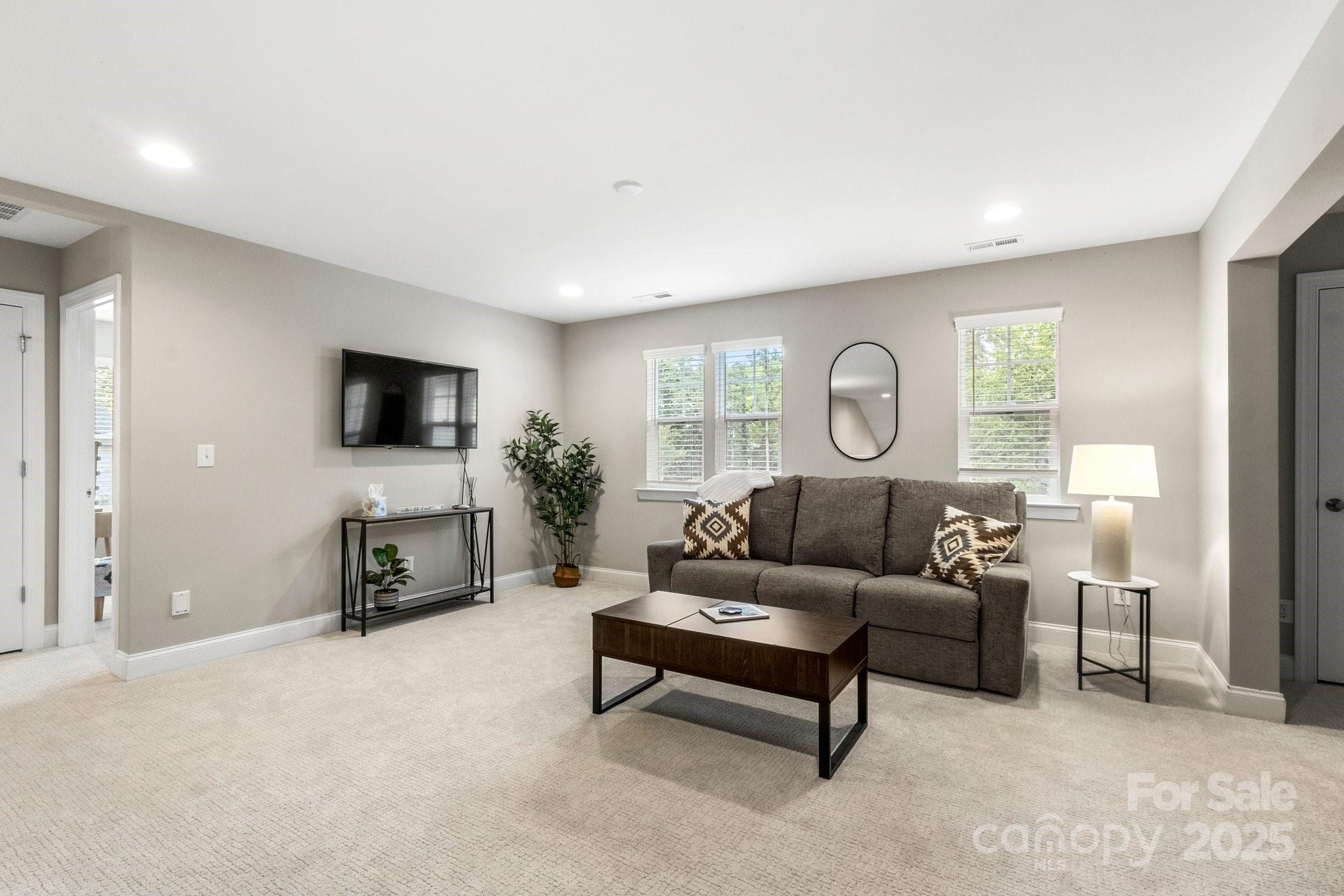 Staged living room with a gray sectional, dark wood coffee table, and wall-mounted television.