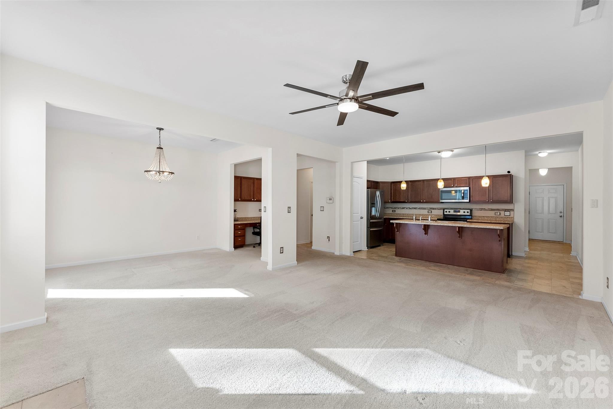 Open living and dining area leading to a kitchen with dark wood cabinets and a large island.
