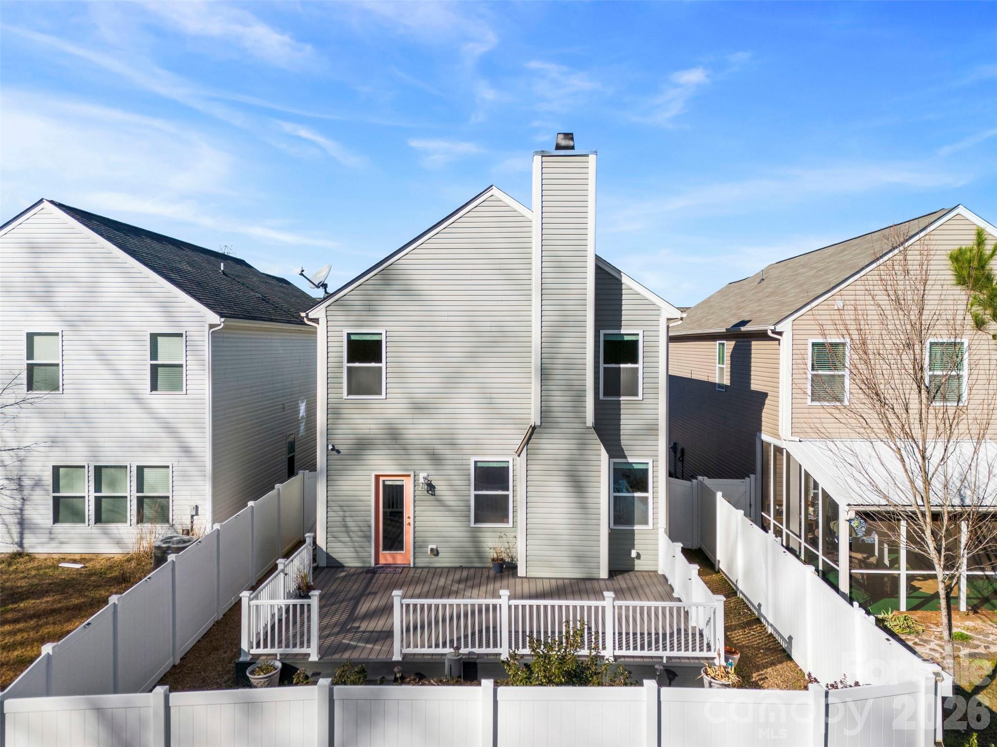 Rear of a gray two-story home with a raised deck and fenced backyard.