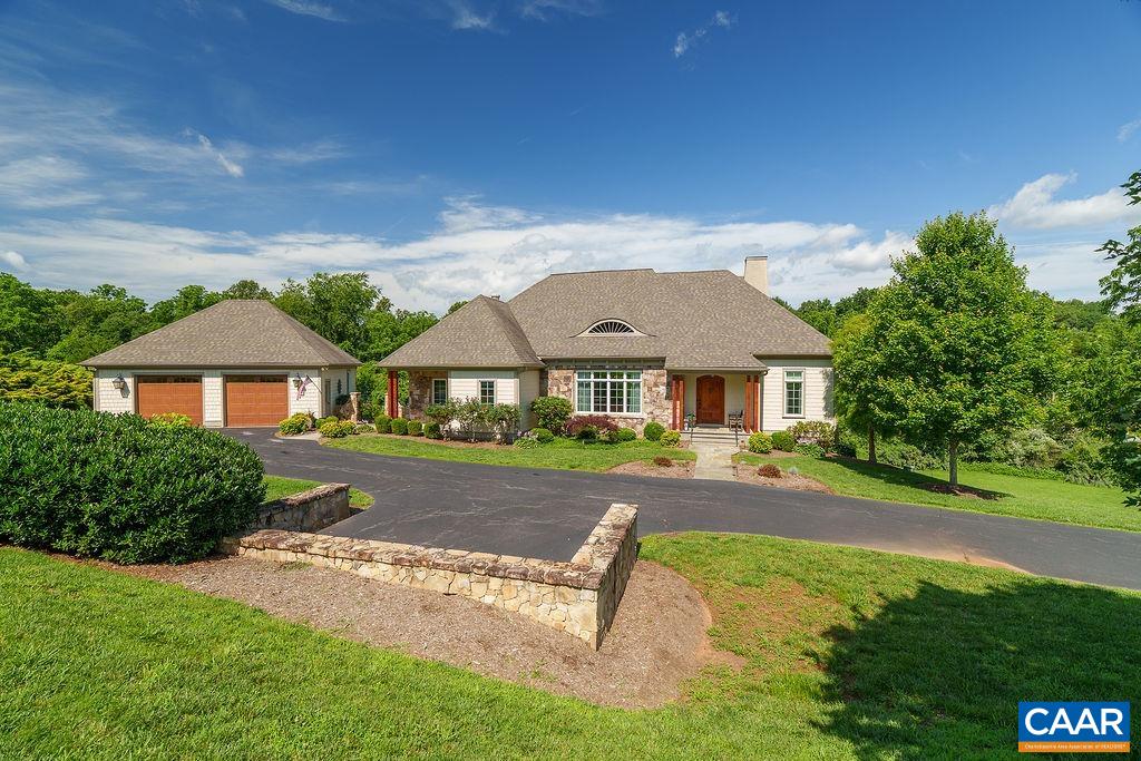 Stone-and-siding home with a two-bay garage, curved driveway, and landscaped front lawn.