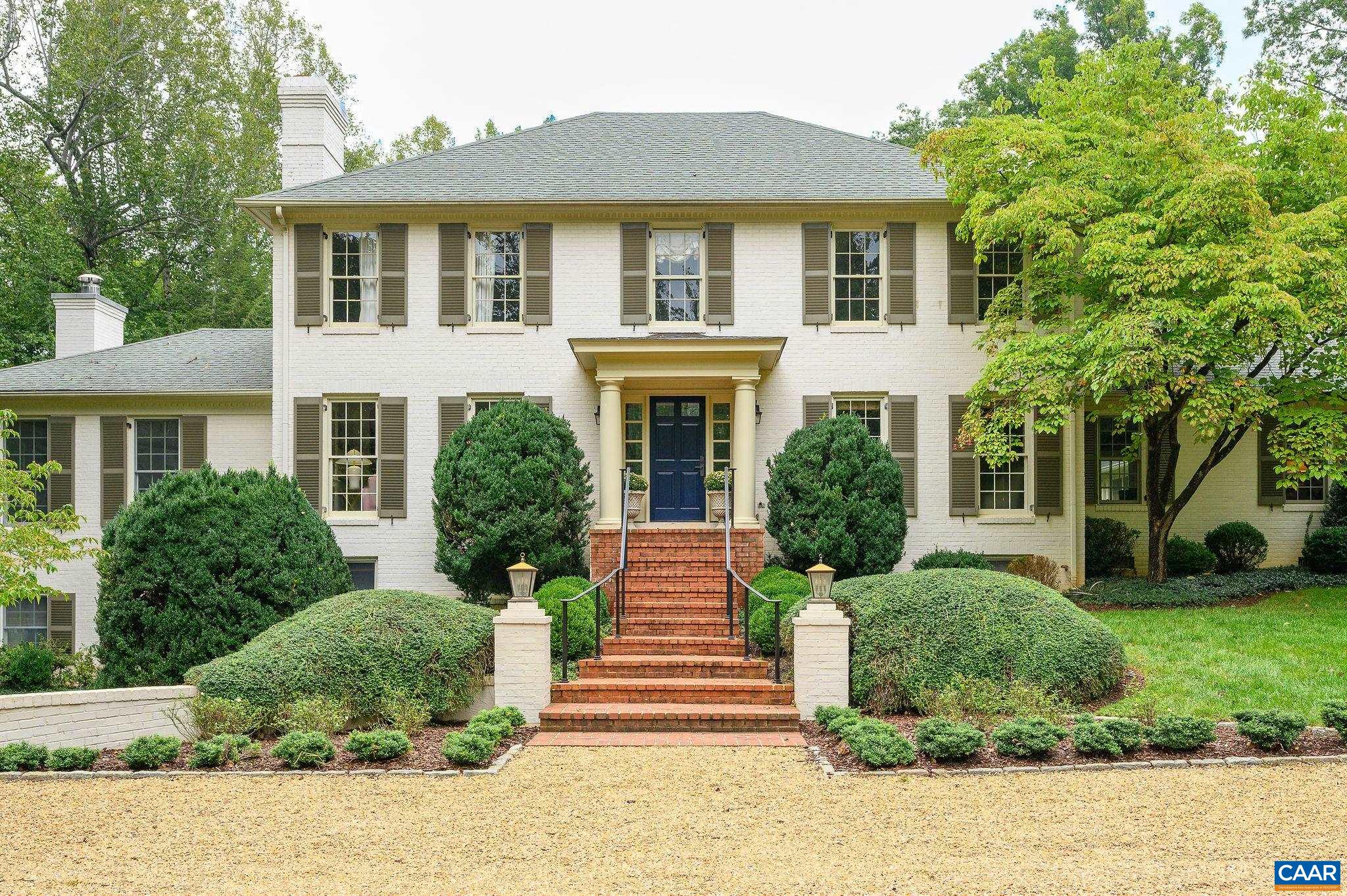 White brick house with brown shutters, blue front door, and broad brick steps.