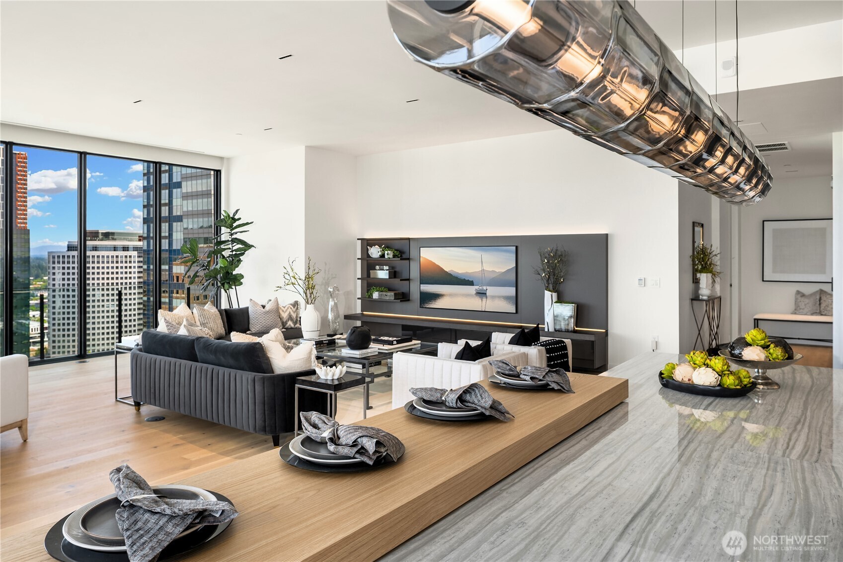 Staged condo living and dining area with floor-to-ceiling windows overlooking Bellevue buildings.