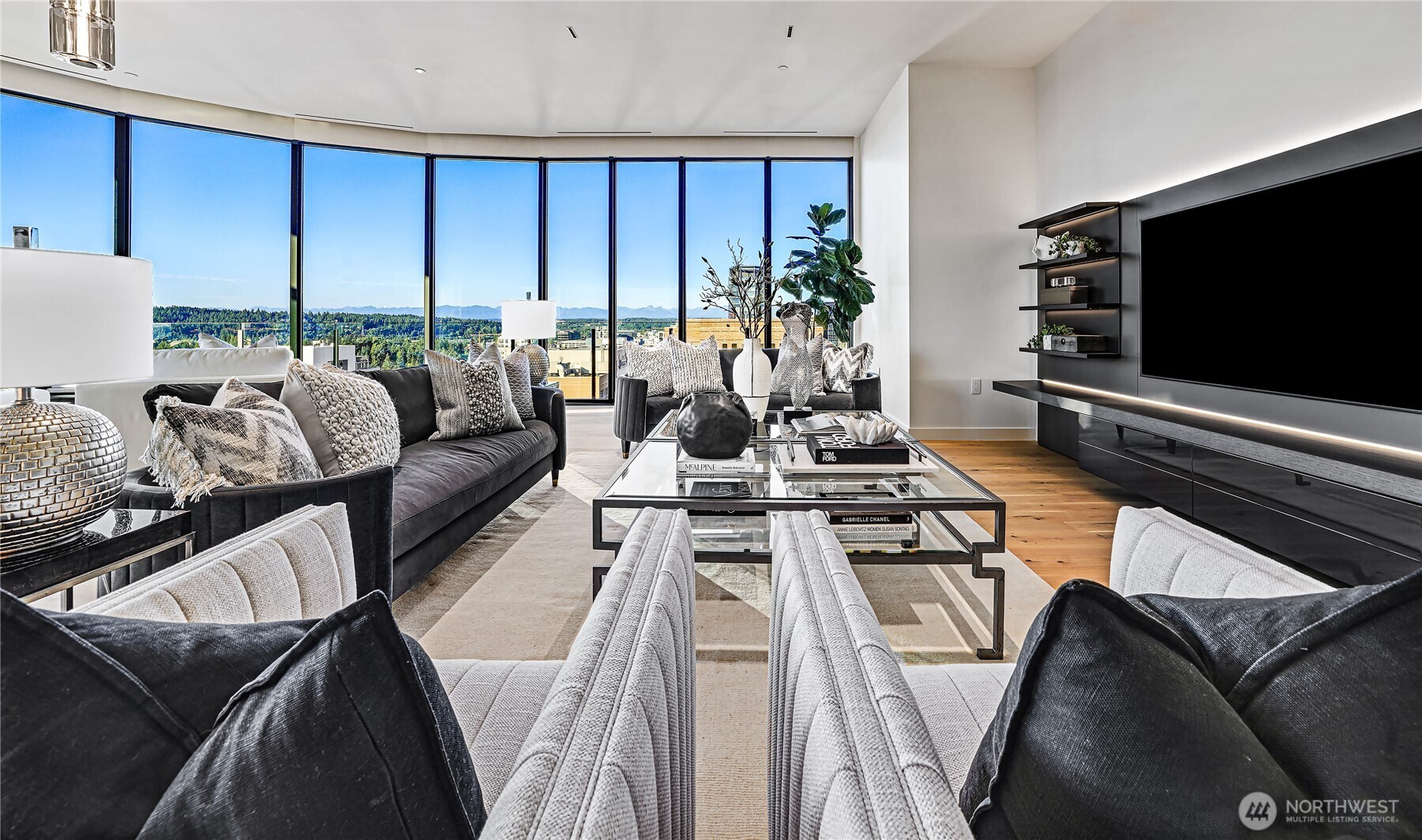 Staged living room with floor-to-ceiling windows overlooking greenery and distant mountains.